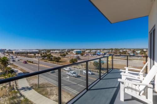 a balcony with two white chairs and a view of a street at Modern 4 BR Luxury Condo with Rooftop Pool Next to the Hangout! in Gulf Shores