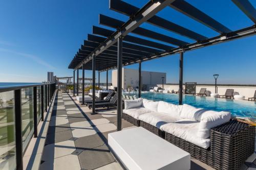 a patio with white couches and a swimming pool at Modern 4 BR Luxury Condo with Rooftop Pool Next to the Hangout! in Gulf Shores