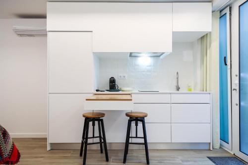 a kitchen with white cabinets and two bar stools at Estúdio Cândida, One place … in Nazaré