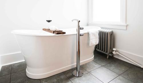 a white bath tub in a bathroom with a radiator at The Armstrong Hotel in Fort Collins