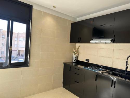 a kitchen with black cabinets and a window at Luxury appartement Fes in Fez