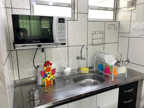 a kitchen counter with a sink and a microwave at Pousada Moça Bonita in Ubatuba