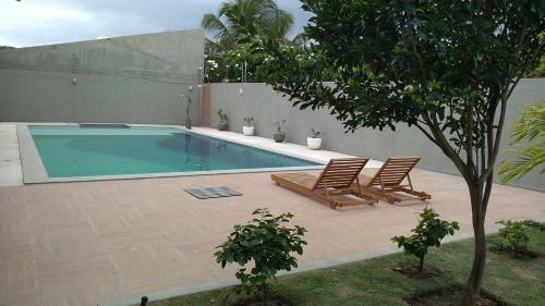 een zwembad met 2 ligstoelen en een boom bij Casa Aruana in Aracaju