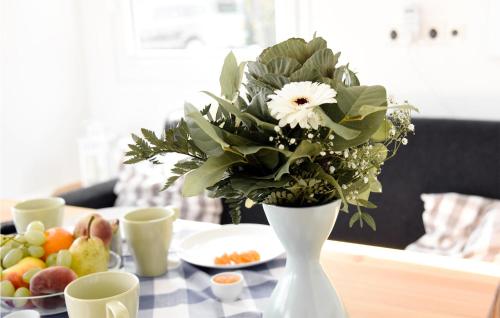 a white vase with flowers on a table with fruit at Cozy Ship In Rheinsberg Hafendorf With House Sea View in Rheinsberg