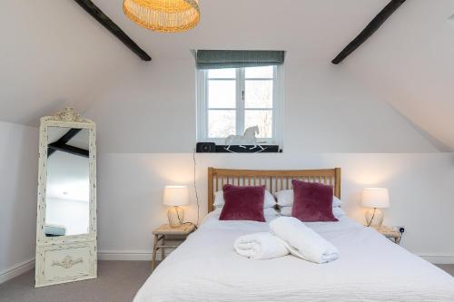 a bedroom with a bed and a mirror at Barn Cottage -Westerlands in Graffham