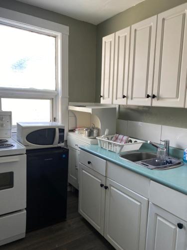 a kitchen with white cabinets and a sink and a microwave at Maryland Homestay in Winnpeg downtown in Winnipeg