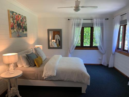 ein Schlafzimmer mit einem Bett und zwei Fenstern in der Unterkunft Gypsy Falls Exclusive Bungalows in Lorne