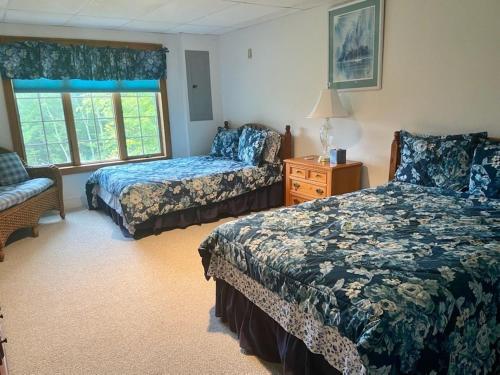 a bedroom with two beds and a chair and a window at Highland Woods - Private home on 37 acres with stunning mountain views in Shaftsbury