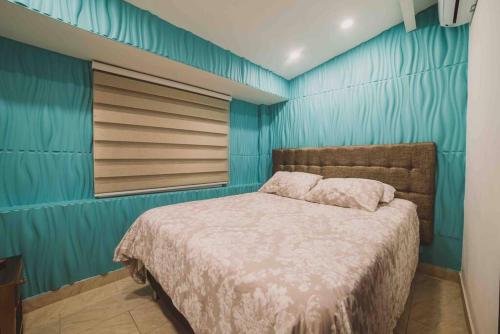 1 dormitorio con cama y pared azul en PARQUELLERAS11BEDROOM! POOL+Jacuzzi BEST LOCATION!, en Medellín