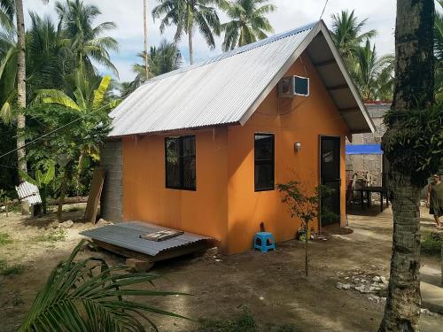 Small cosy house (simple but complete) في Asgad: منزل برتقالي صغير بسقف معدني
