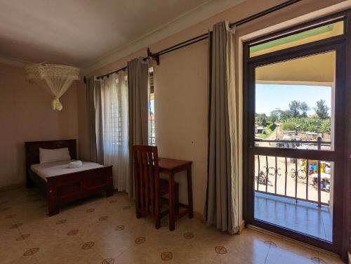 Habitación con cama, ventana y mesa. en Kasenene Legacy Hotel en Fort Portal