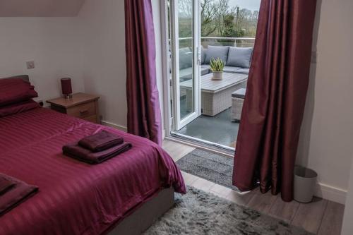 a bedroom with a bed and a window with a patio at Chy Lowen, great valley views from balcony in Hayle