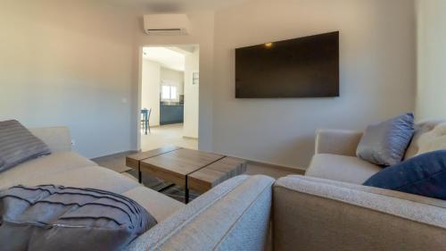 a living room with two couches and a flat screen tv at Kefalonian Gems in Pesádha