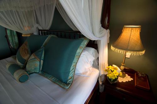 a bed with blue pillows and a lamp on a table at Spring Hotel Bequia in Port Elizabeth
