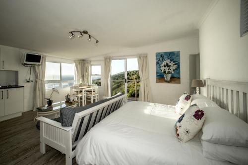 1 dormitorio con 1 cama blanca grande y ventana en Rocklands Seaside Bed and Breakfast, en Simonʼs Town