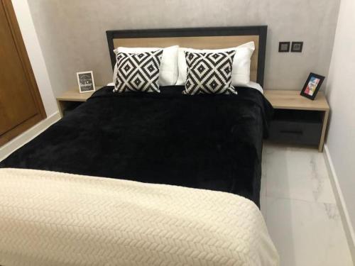 - une chambre avec un lit doté d'une couverture et d'oreillers noirs dans l'établissement Appart luxueux sécurisé parking 10 min Medina, à Fès