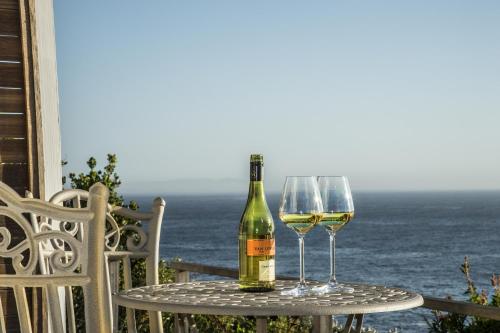 a bottle of wine and two glasses on a table at Rocklands Seaside Bed and Breakfast in Simonʼs Town