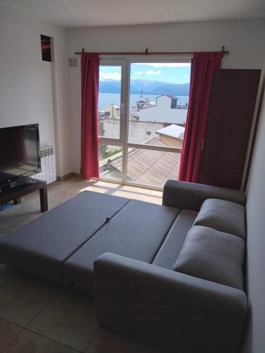 a living room with a couch and a large window at Departamento JS - Centro Bariloche in San Carlos de Bariloche