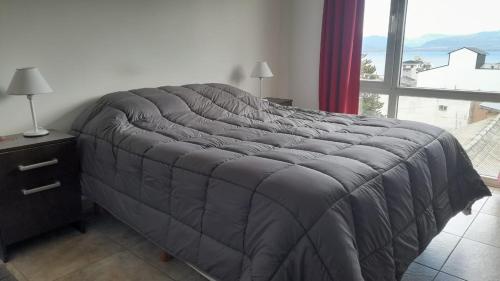 Ce lit se trouve dans une chambre dotée d'une grande fenêtre. dans l'établissement Departamento JS - Centro Bariloche, à San Carlos de Bariloche