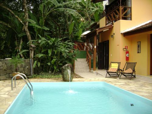 a swimming pool with a fountain in a yard at Vila São Pedro in Ilhabela