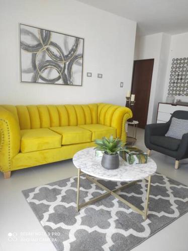 a living room with a yellow couch and a table at Condominio Palomino en Viñedos del Mar Ensenada privada San Antonio in Ensenada