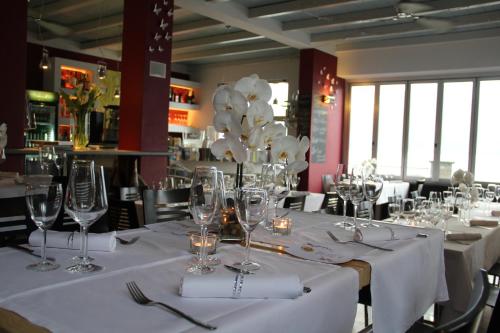a dining room with white tables and chairs with wine glasses at Veranda Beach Apartment in Pianello Del Lario