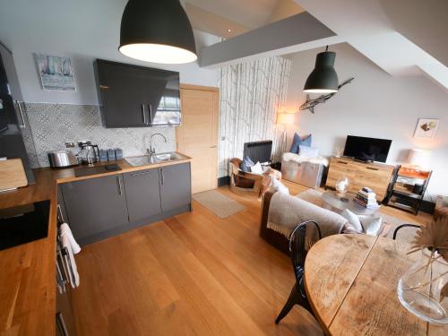 a kitchen and a living room with a table at Padstow Escapes - Pajar Luxury Penthouse Apartment in Padstow