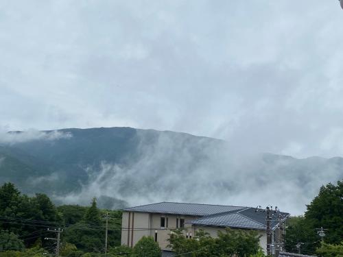 a house in front of a mountain with clouds at 金閣莊 private onsen by reservation for free in Hakone