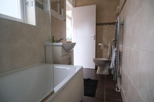 y baño con bañera, lavabo y aseo. en 4 Bedroom House in Turnpike Lane/Wood Green, en Londres