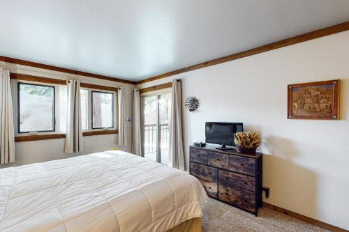 een slaapkamer met een bed, een tv en ramen bij Mountainback 47 in Mammoth Lakes