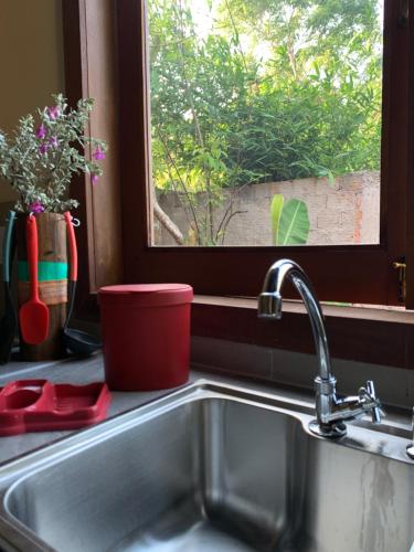 a kitchen sink with a red container next to a window at Quintal de Barros in Arraial d'Ajuda