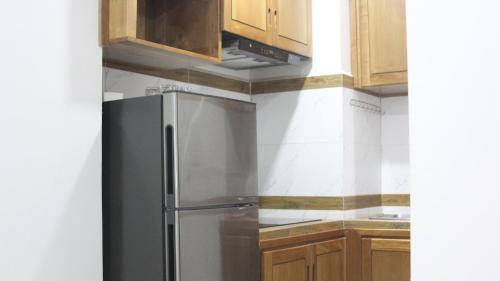 a stainless steel refrigerator in a kitchen with wooden cabinets at Ptas Tauch Residence in Phnom Penh