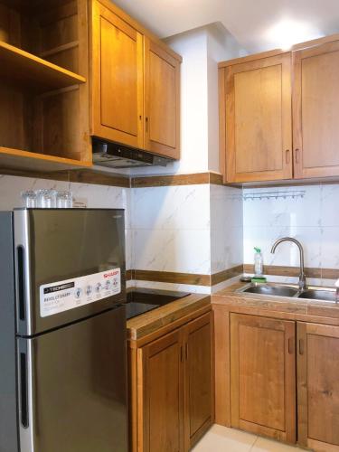 a kitchen with wooden cabinets and a stainless steel refrigerator at Ptas Tauch Residence in Phnom Penh