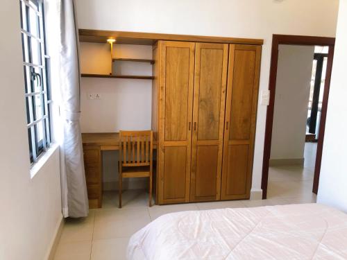 a bedroom with a wooden cabinet and a desk at Ptas Tauch Residence in Phnom Penh