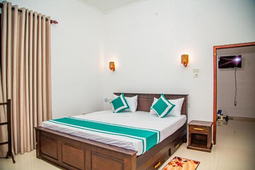 um quarto com uma cama com almofadas azuis e verdes em Chala Villa em Ambalangoda