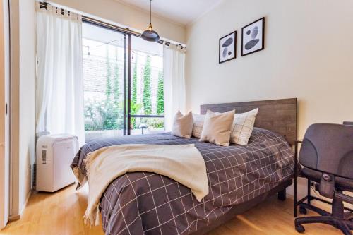 a bedroom with a bed and a chair and a window at San Carlos rentals - Lastarria in Santiago