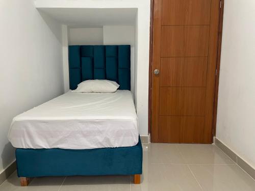 1 cama con cabecero azul y puerta de madera en Home Mariana, en Trujillo