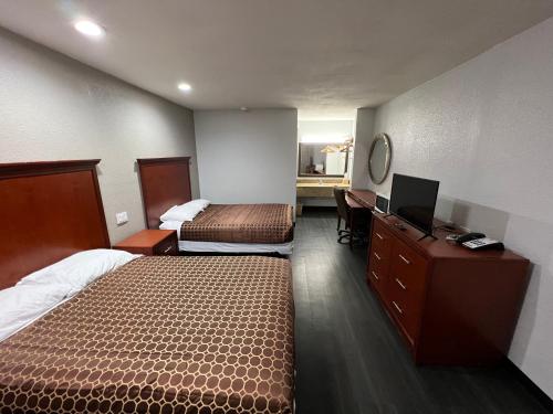 a hotel room with two beds and a desk at Scottish inns Jonesboro in Jonesboro