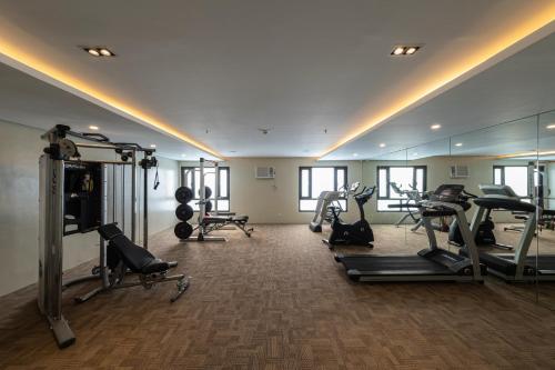 a gym with several tread machines and a mirror at Cebu Family Suites powered by Cocotel in Cebu City