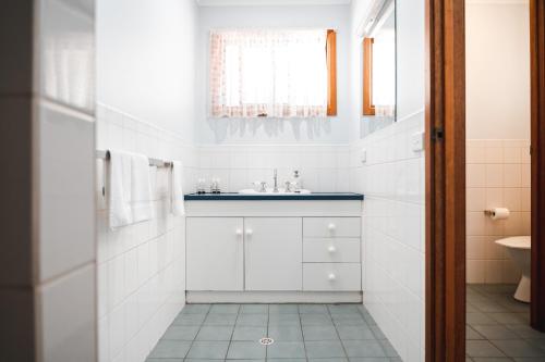 Baño blanco con lavabo y aseo en Riverbush Cottages, en Monash