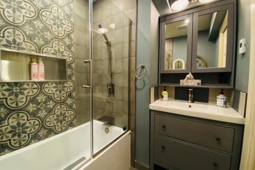 a bathroom with a shower and a sink and a mirror at Neocolonial Nouveau Kensington in Vancouver