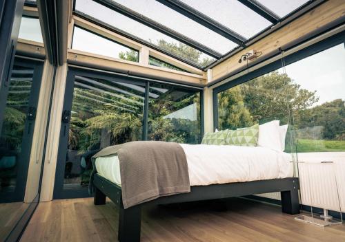 a bedroom with a bed in a glass house at Hananui PurePod in Stewart Island