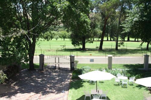 a fence with tables and chairs and an umbrella at Greenfields Guesthouse & Restaurant in Alberton