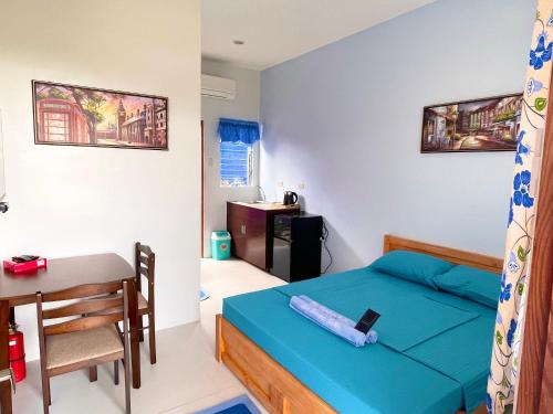 a bedroom with a bed and a table and a desk at Blue Summer Suites in Bingag