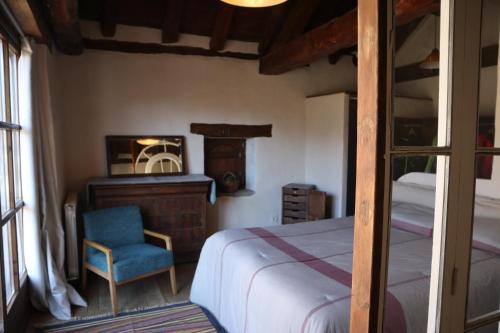 1 dormitorio con cama, silla y espejo en Casa Chidro, en Buesa