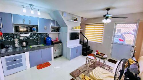 a kitchen with blue cabinets and a living room at HOMESTAY BY ERNZ in Butuan