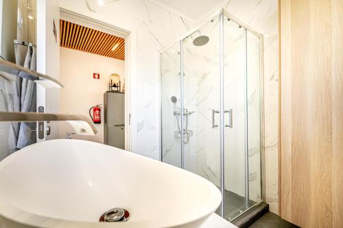 La salle de bains est pourvue d'une douche et d'un lavabo blanc. dans l'établissement Two bedroom apartment close to train station by Lisbon with Sintra, à Queluz