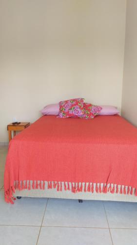 een bed met een rode deken en een kussen erop bij Suíte Porto das Dunas in Salvador