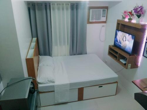 a small bedroom with a bed and a tv at Grand reviera in the front of famous sunset of manila with stunning beauty of dolomite sand in Manila