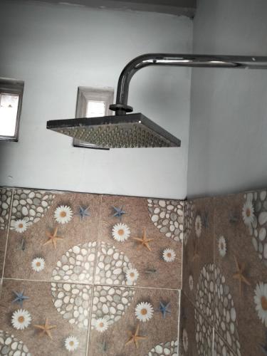ein Bad mit einer Dusche mit einem Waschbecken und Fliesenboden in der Unterkunft Marselino Bacpacker's Room in Bajawa